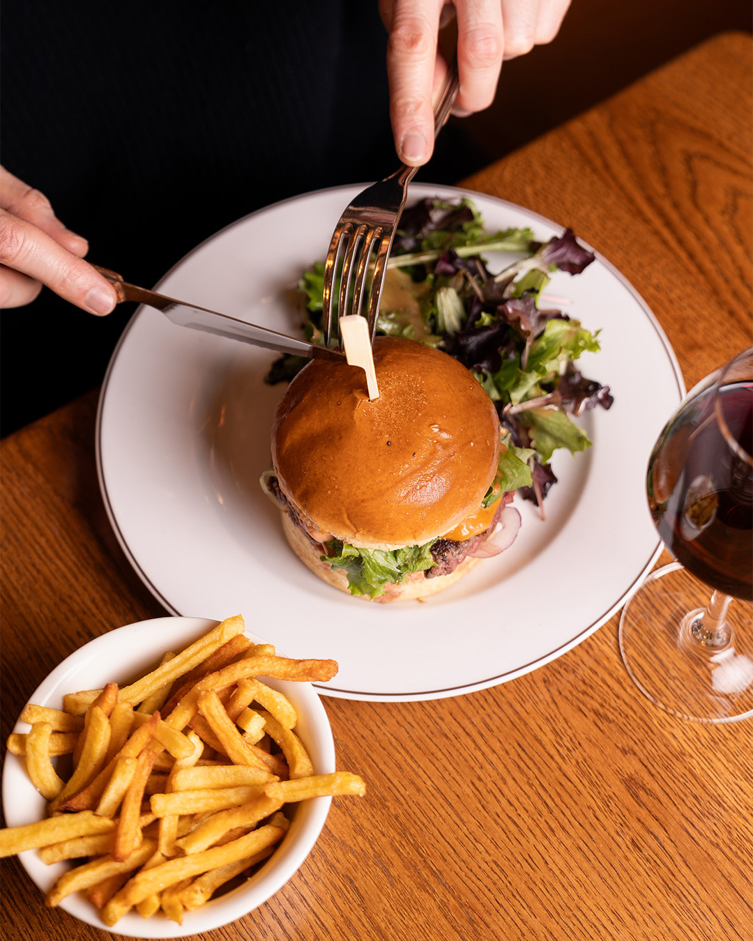 Burger servi avec frites et salade sur une table en bois