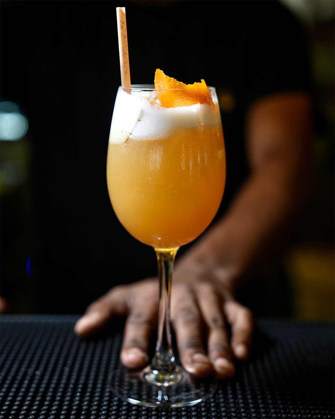 Cocktail orangé servi dans un verre à pied avec zeste d’orange